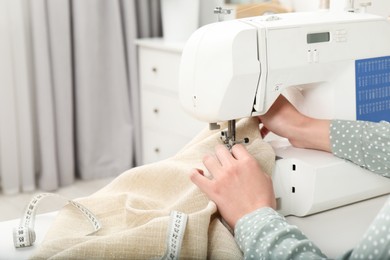 Photo of Seamstress working with sewing machine indoors, closeup
