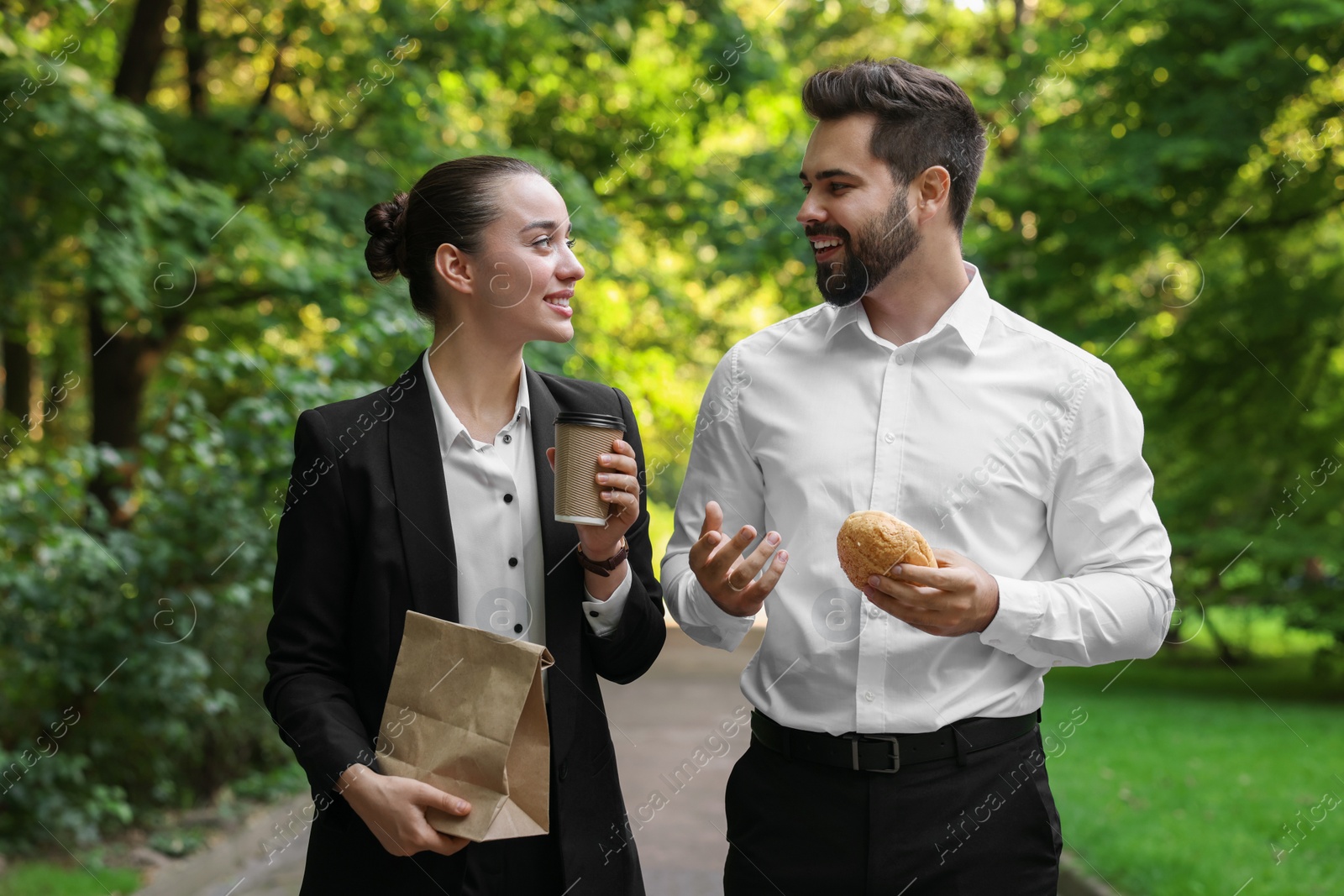 Photo of Business lunch. Happy colleagues spending time together during break in park