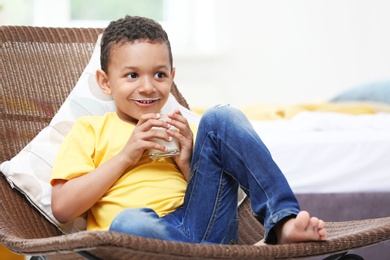 Photo of Adorable African-American boy with glass of milk at home