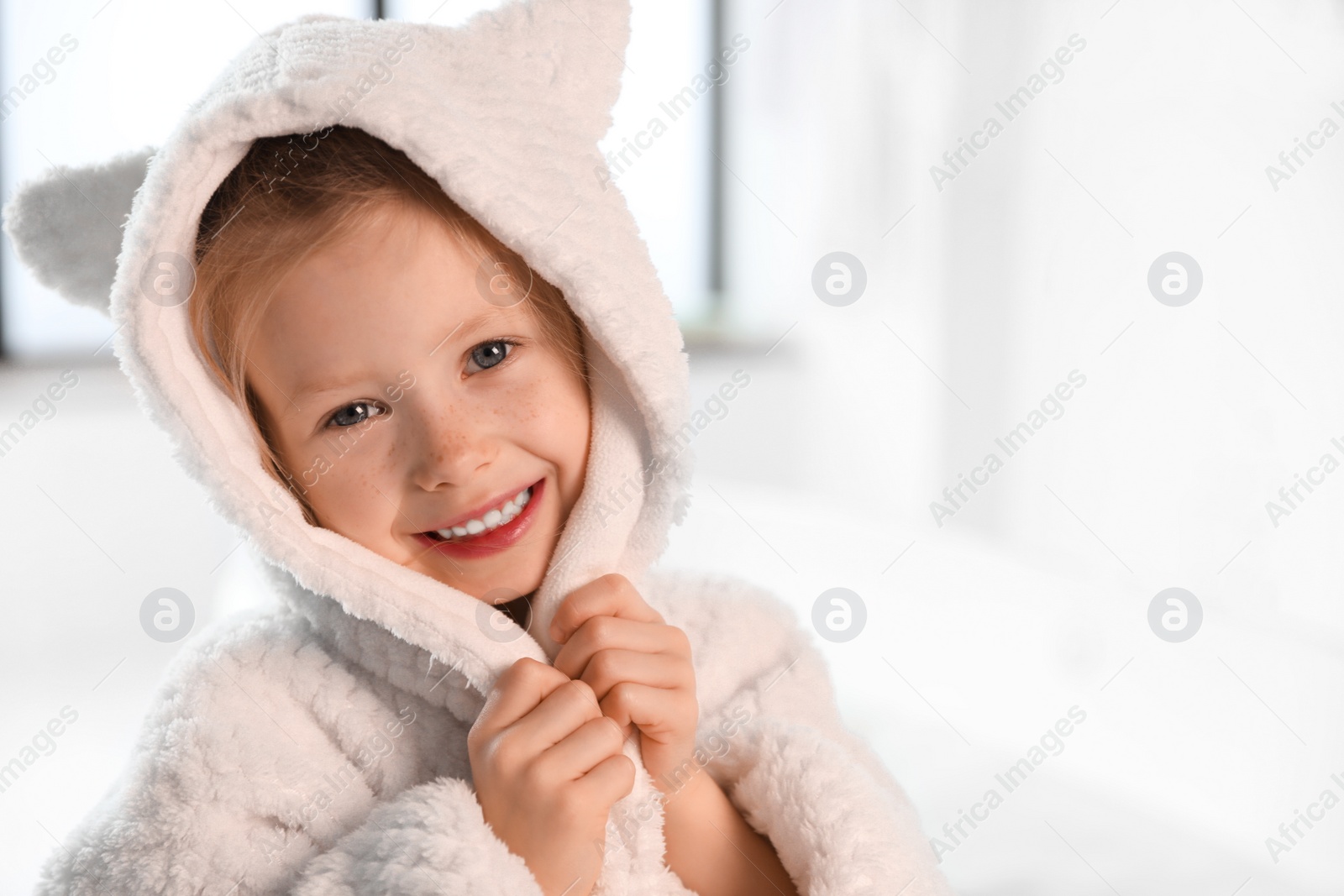 Photo of Cute little girl in bathroom. Space for text