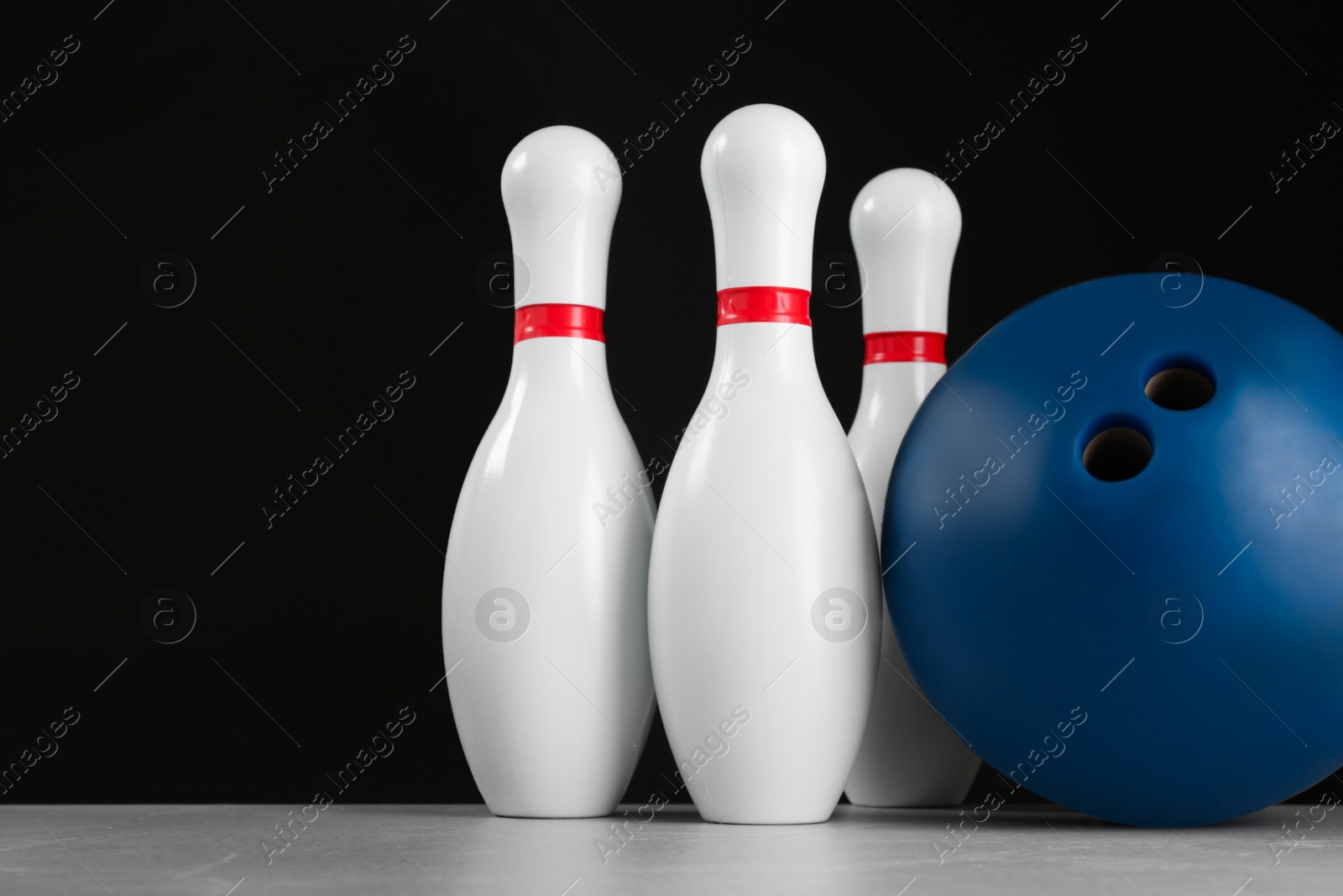 Photo of Blue bowling ball and pins on light grey marble table