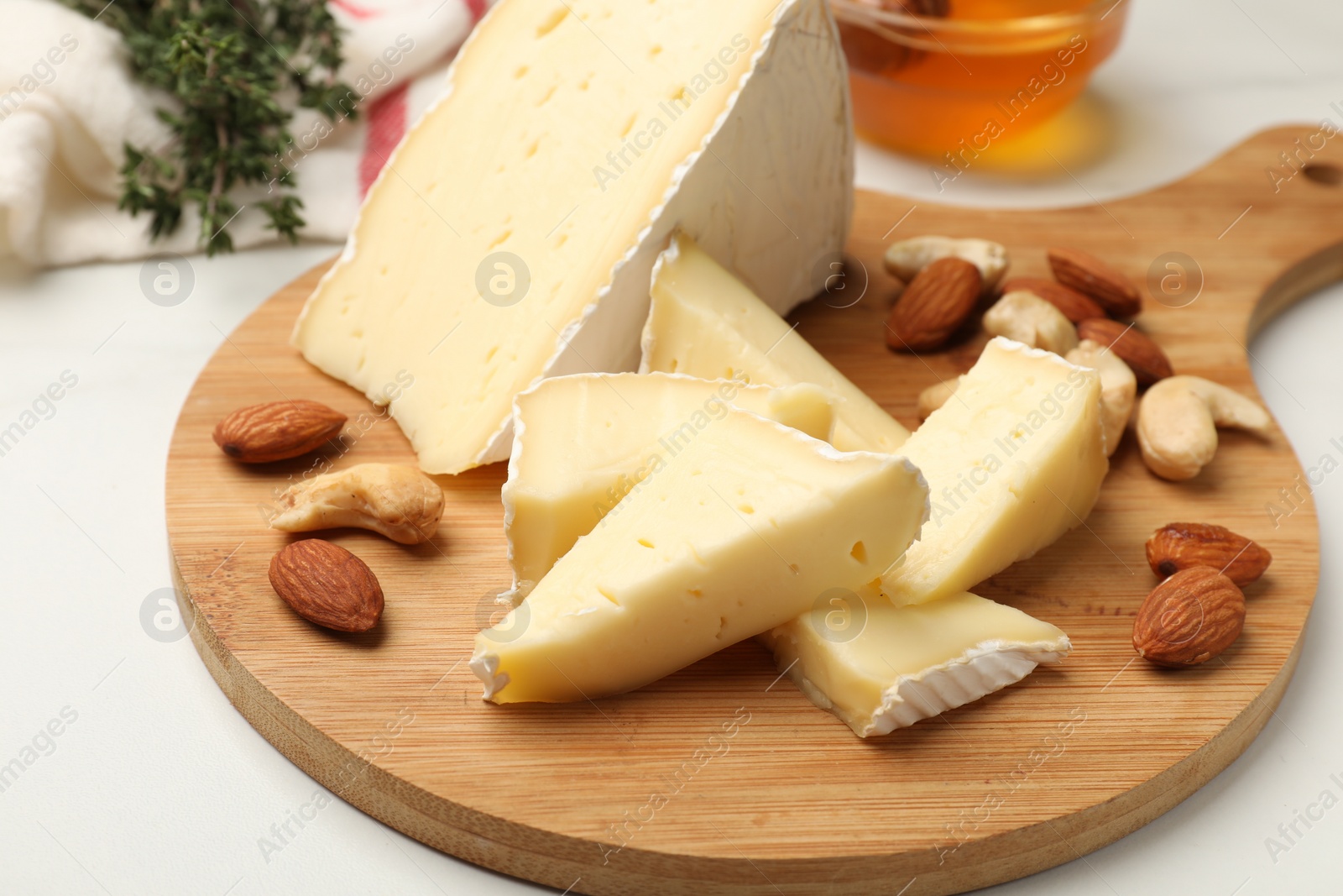 Photo of Tasty Camembert cheese with honey and nuts on white table