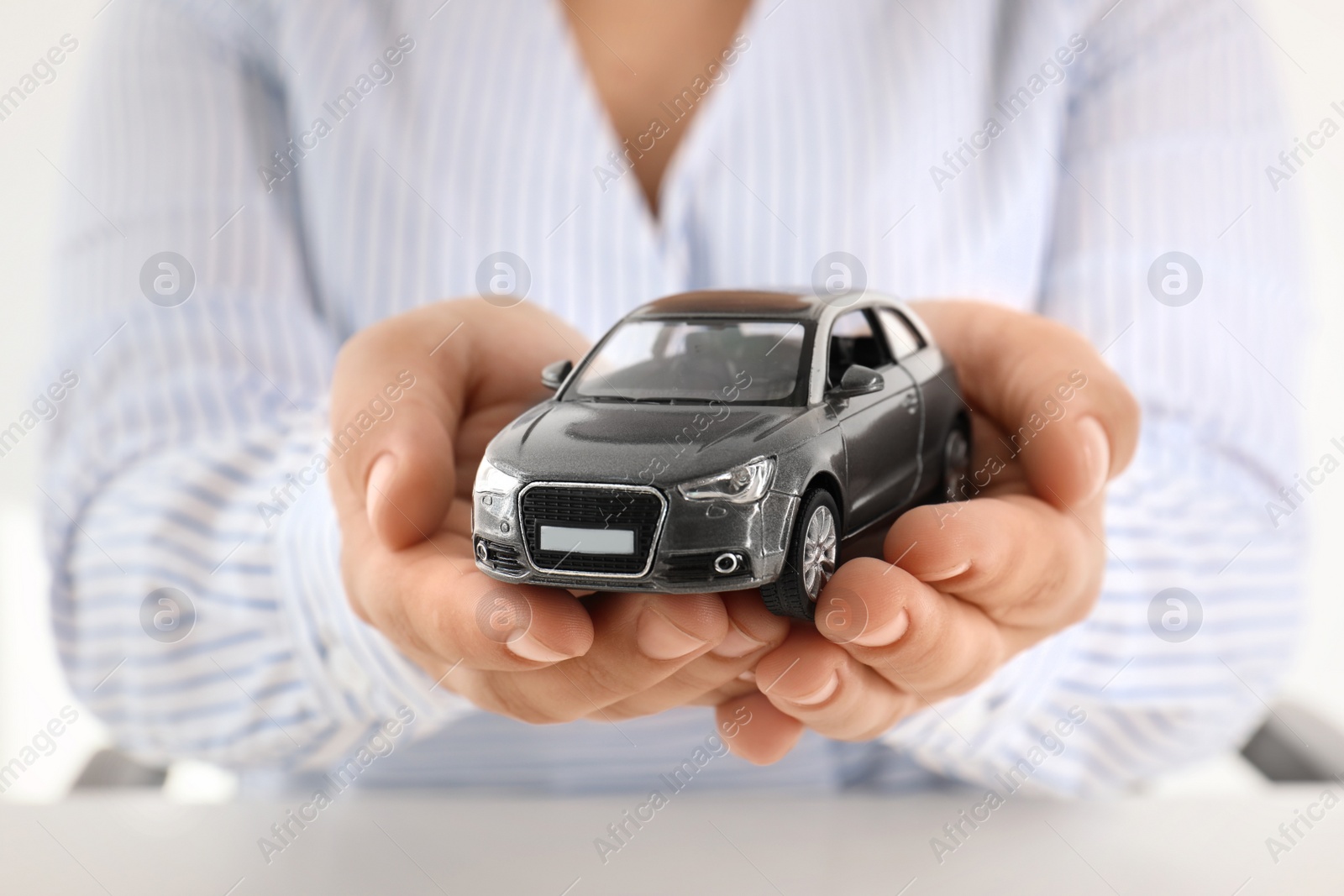 Photo of Female insurance agent holding toy car, closeup