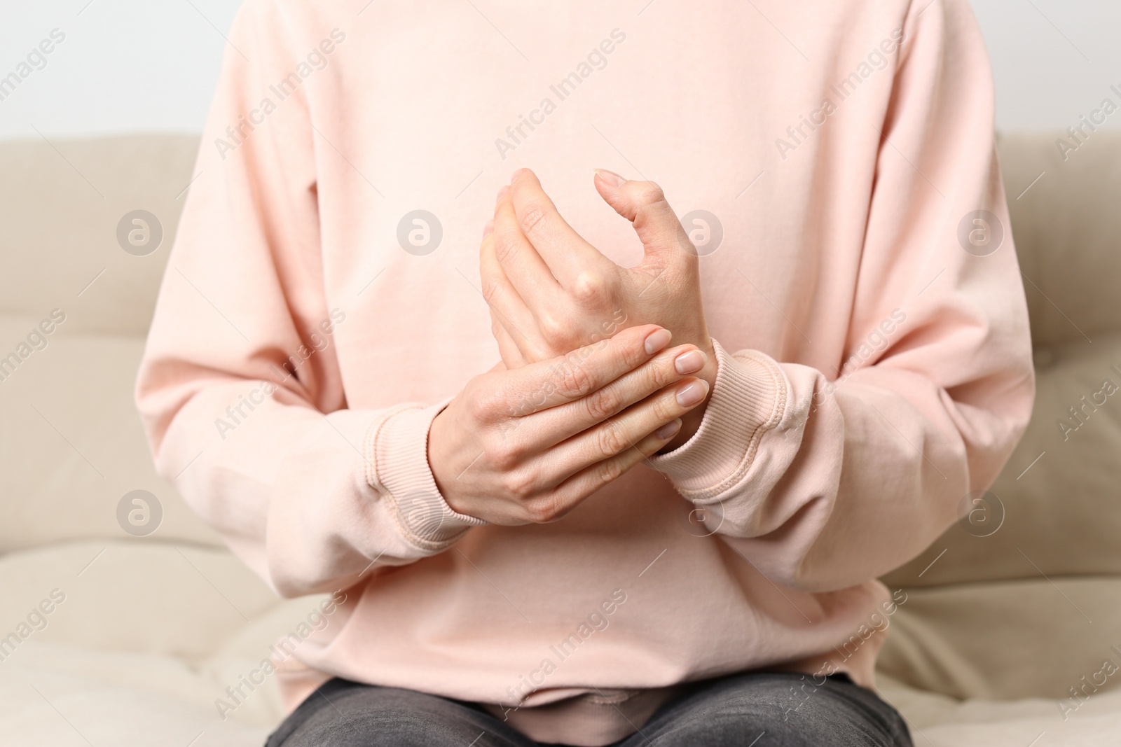 Photo of Woman suffering from trigger finger on sofa, closeup