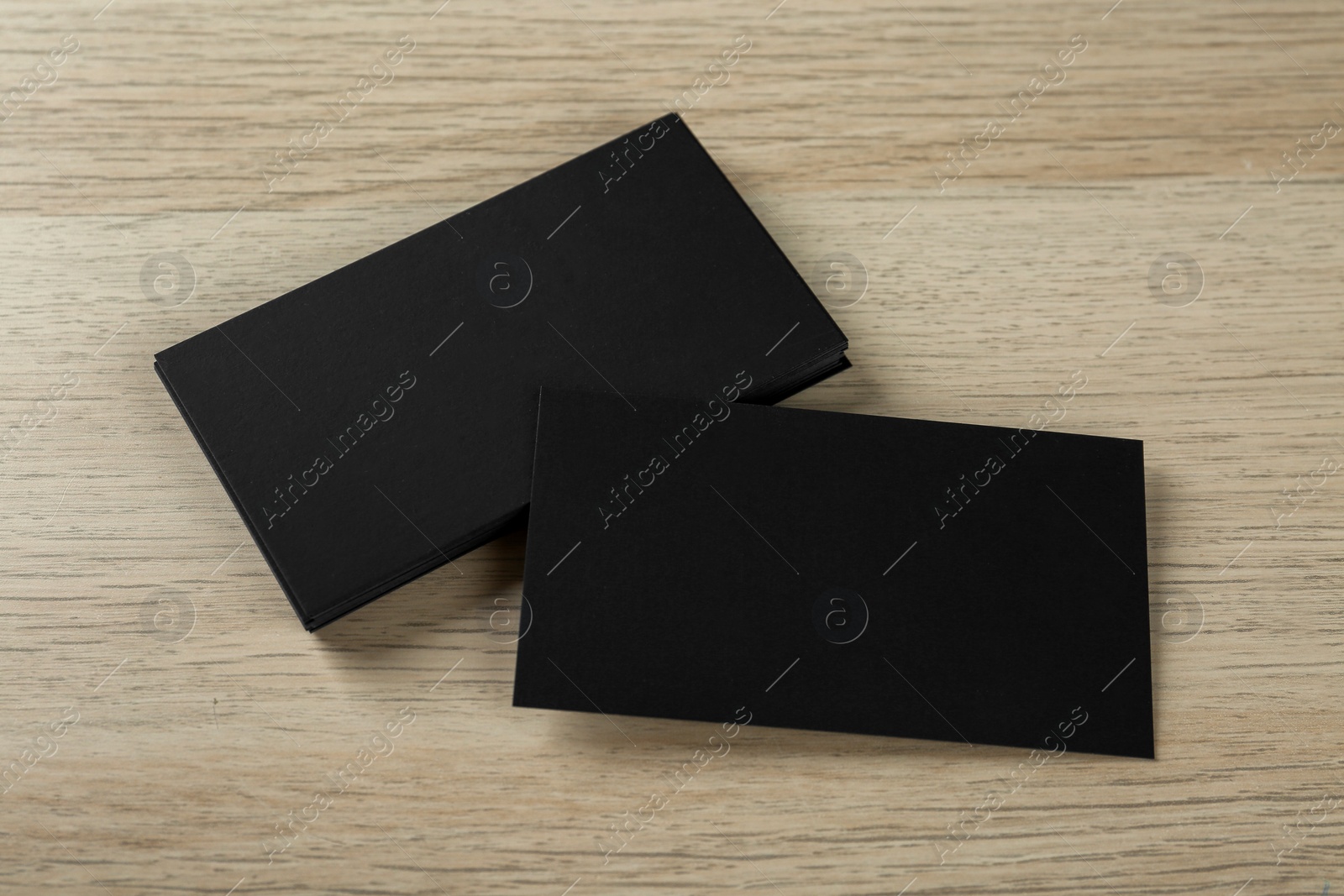 Photo of Blank black business cards on wooden background, above view. Mockup for design