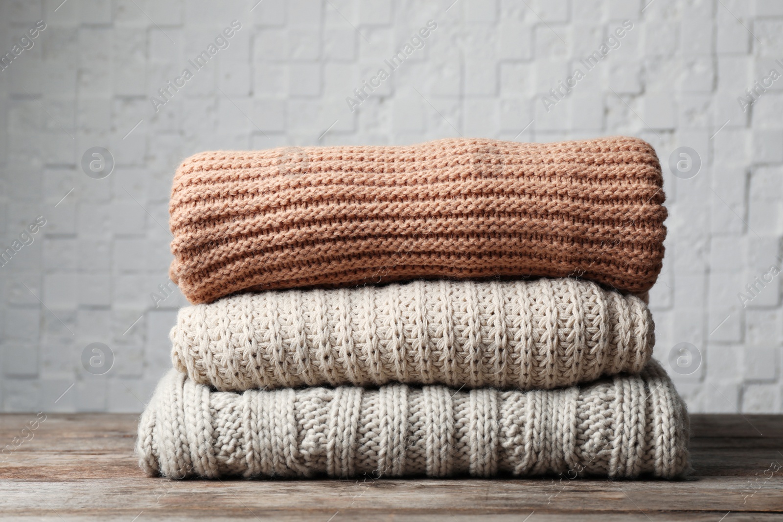 Photo of Stack of folded knitted sweaters on table