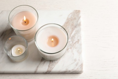 Burning candles in glasses on marble board