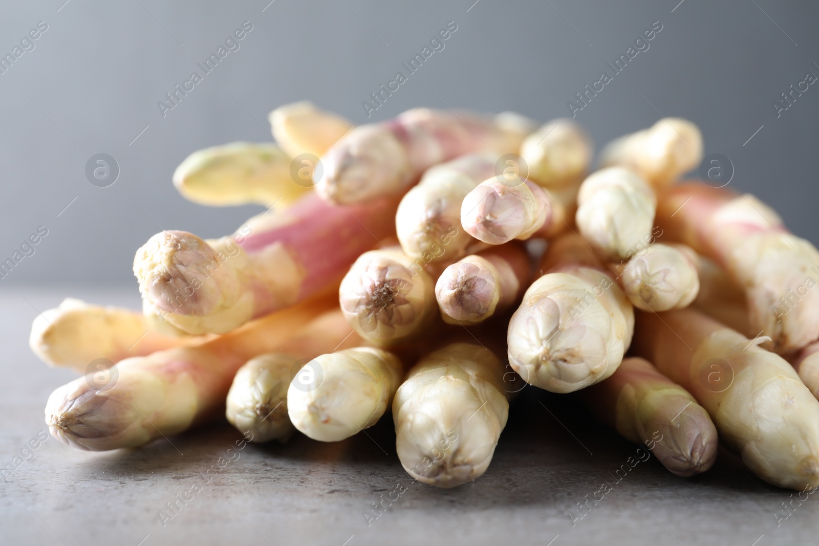 Photo of Pile of fresh white asparagus on grey table, closeup