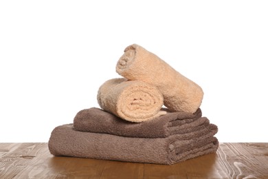 Photo of Soft colorful terry towels on wooden table against white background