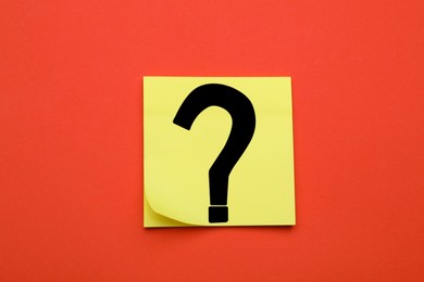 Photo of Sticky note with question mark on dark orange background, top view