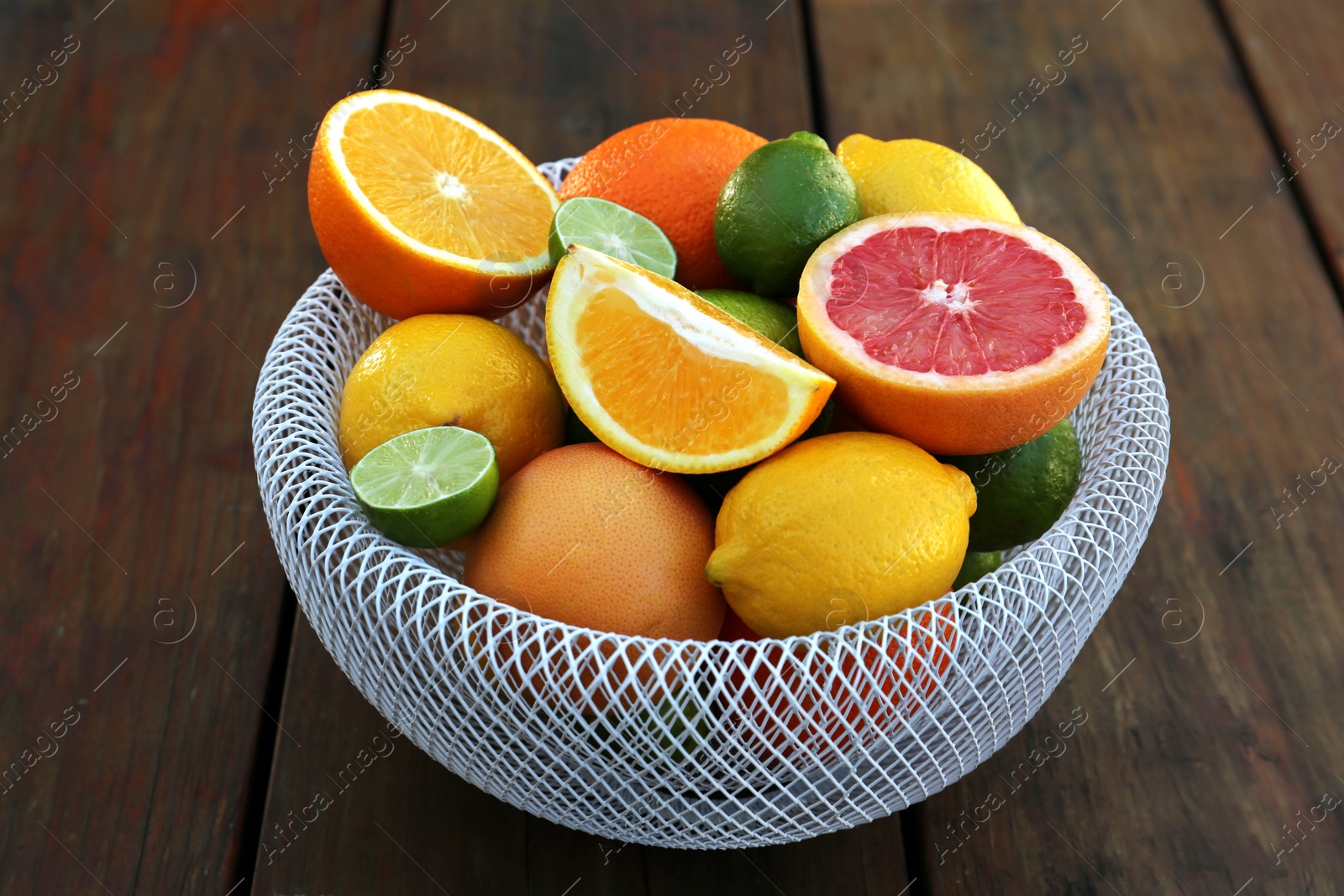 Photo of Bowl with different citrus fruits on wooden table