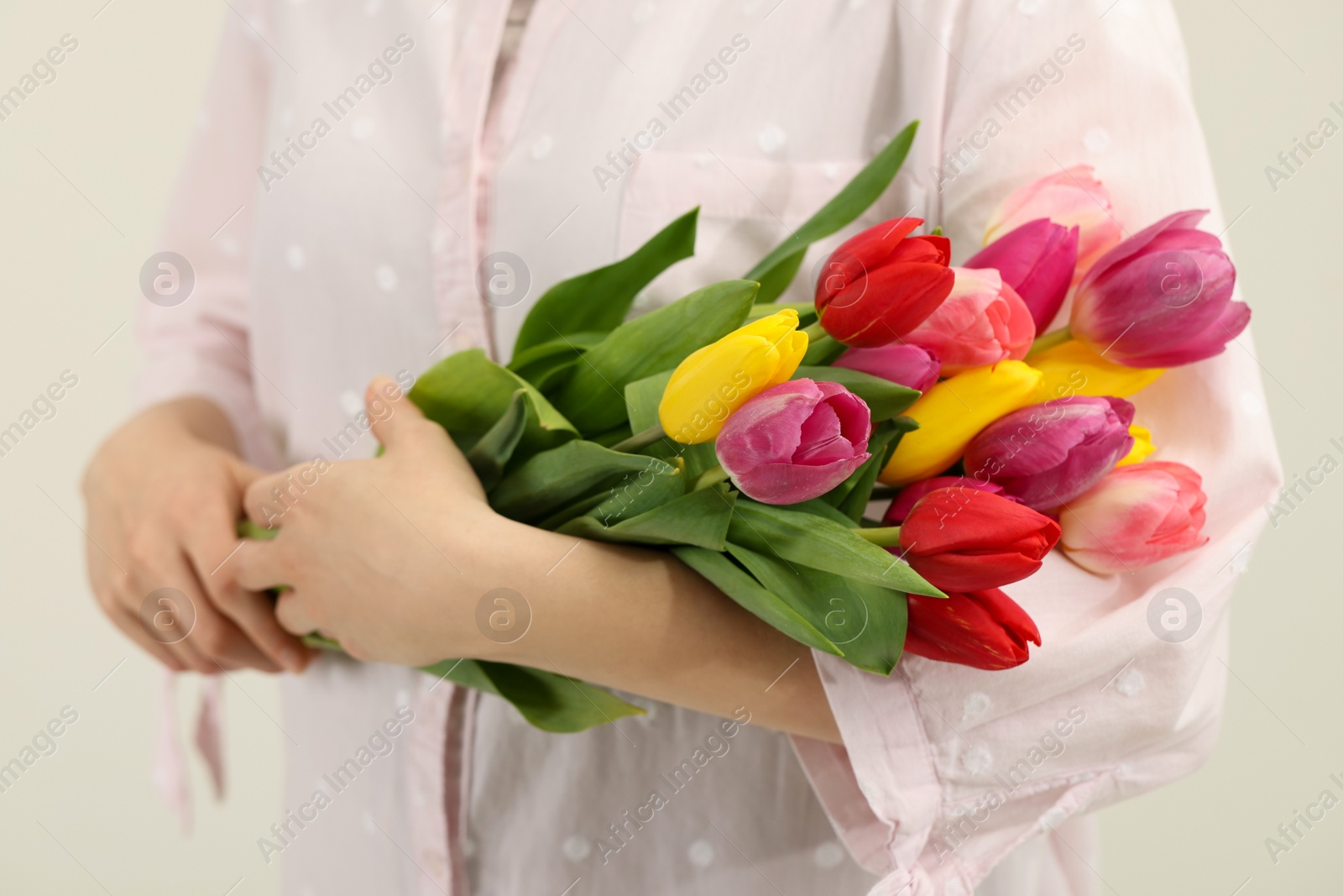 Photo of Woman holding beautiful colorful tulip flowers on white background, closeup