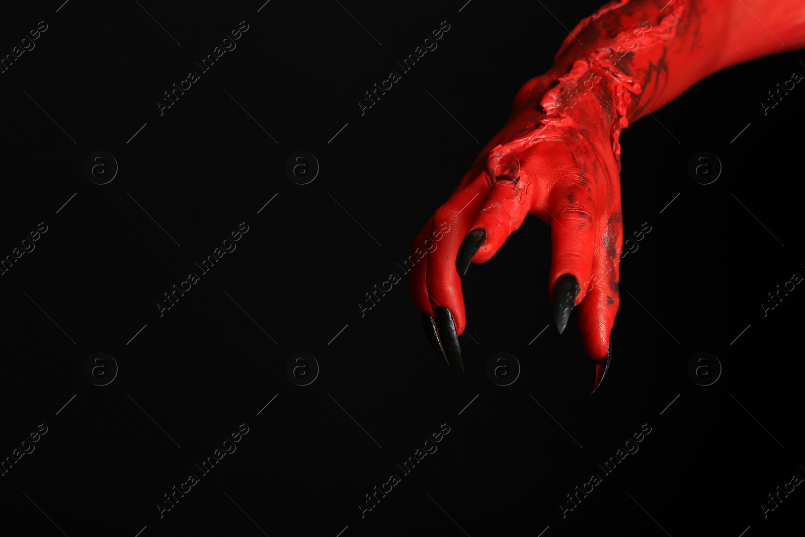 Photo of Scary monster on black background, closeup of hand with space for text. Halloween character