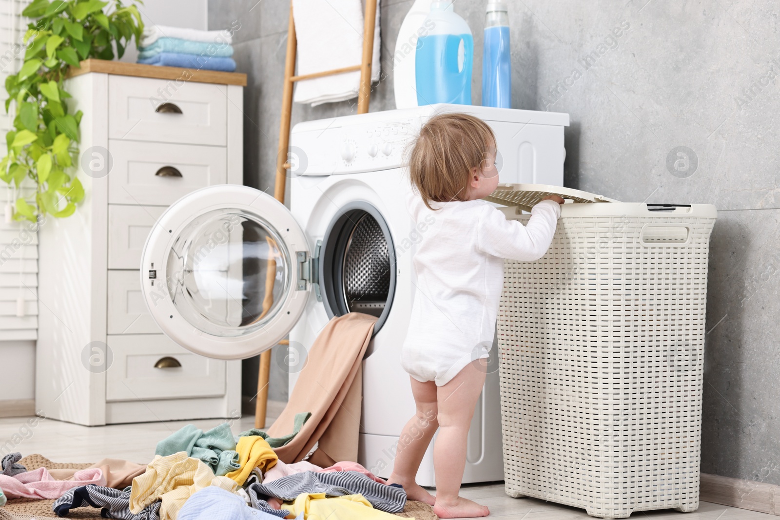 Photo of Little girl among baby clothes in bathroom