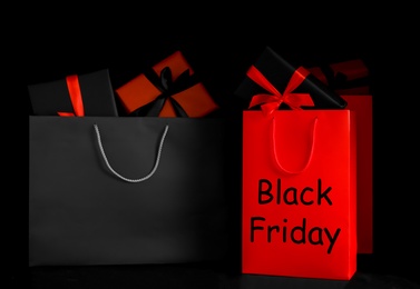 Photo of Paper shopping bags and gift boxes on dark background. Black Friday sale