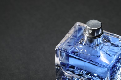 Photo of Blue men's perfume in bottle on black background, closeup. Space for text