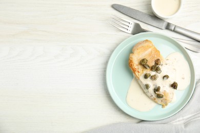 Photo of Delicious cooked chicken fillet with capers and sauce served on white wooden table, flat lay. Space for text