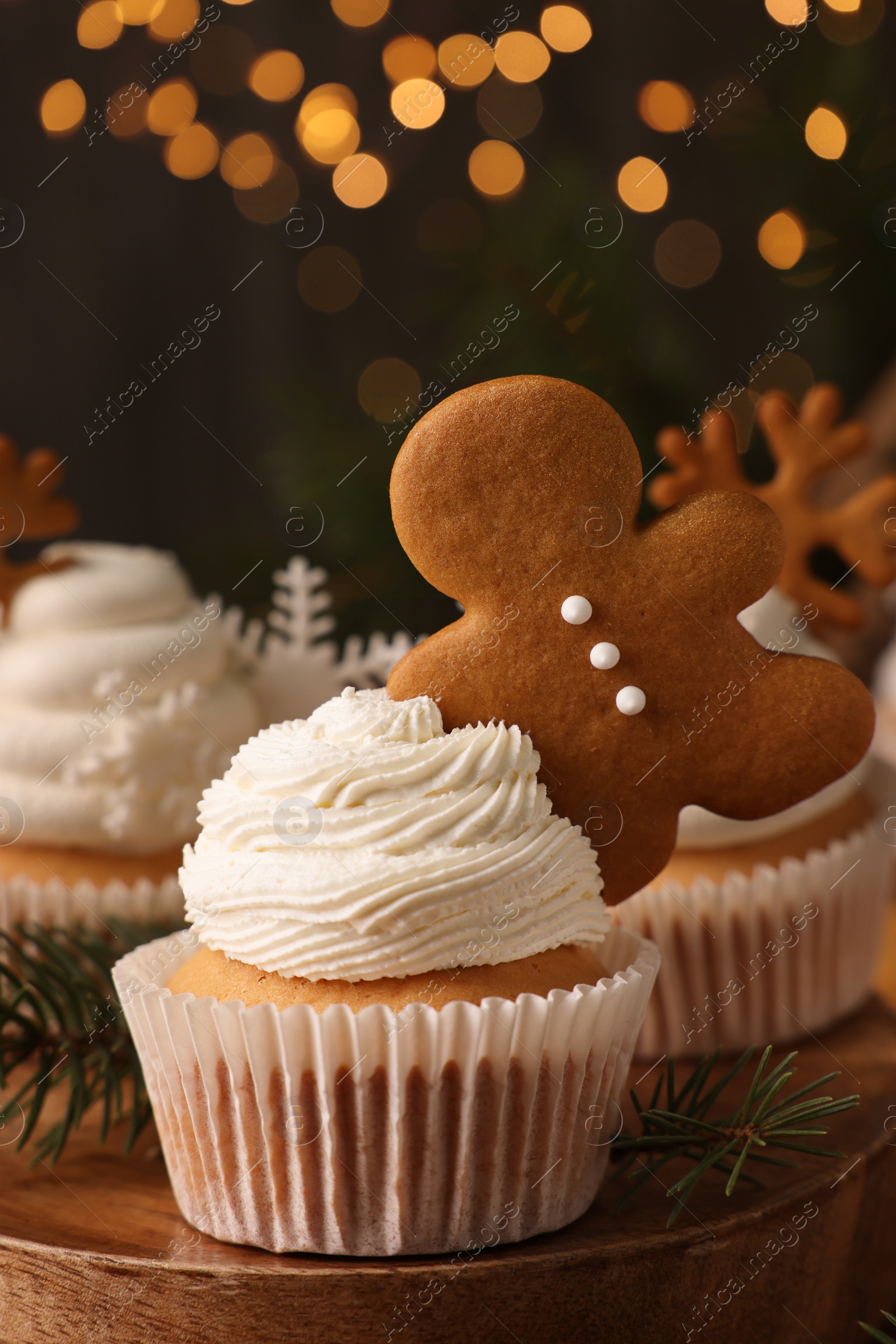 Photo of Tasty Christmas cupcake with gingerbread man and fir branches on wooden board