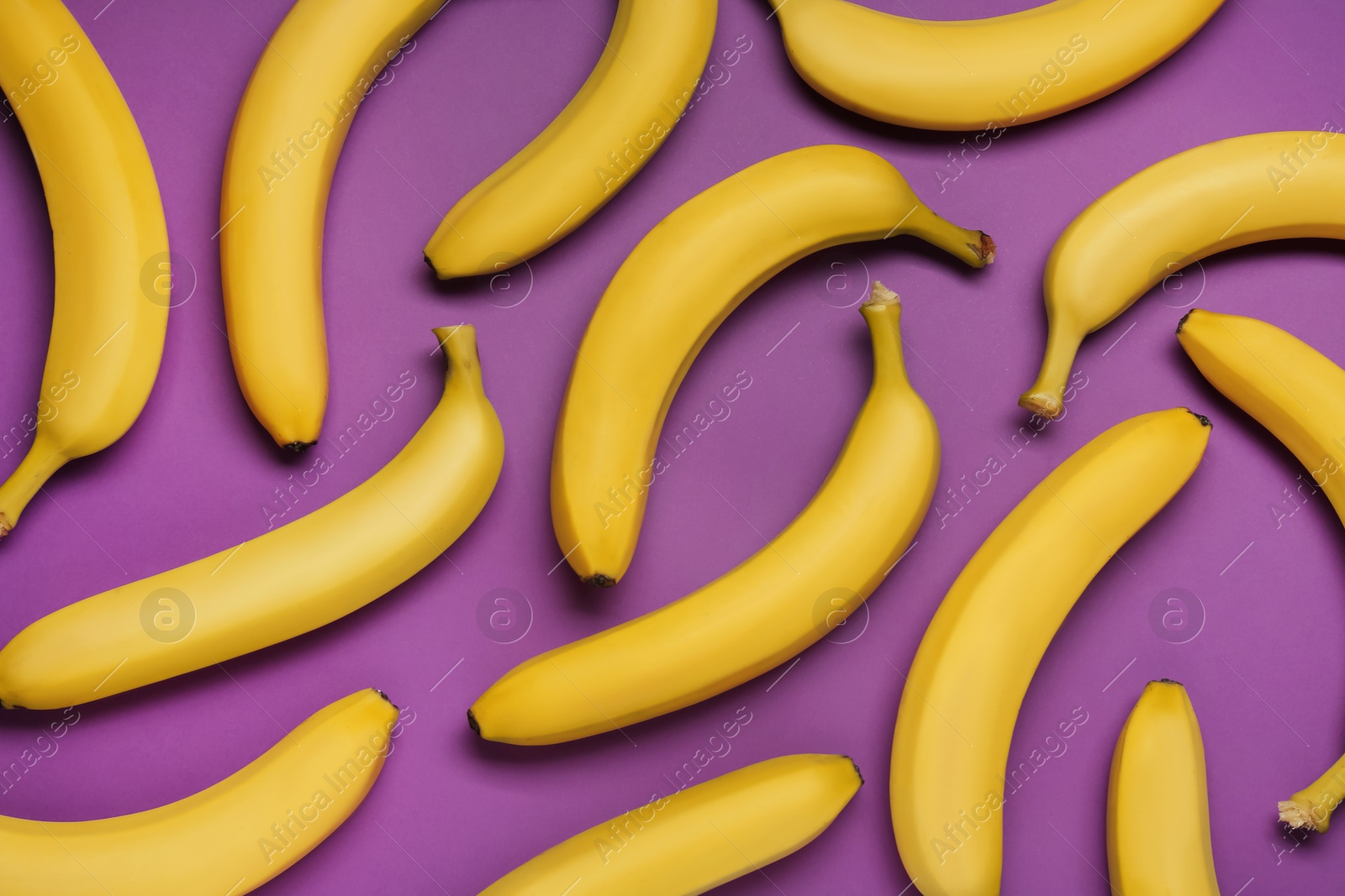 Photo of Ripe yellow bananas on purple background, flat lay