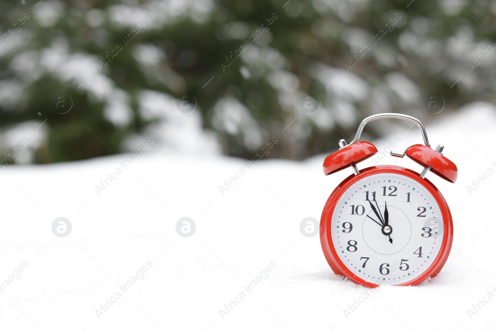 Photo of Red alarm clock on white snow outdoors. Space for text