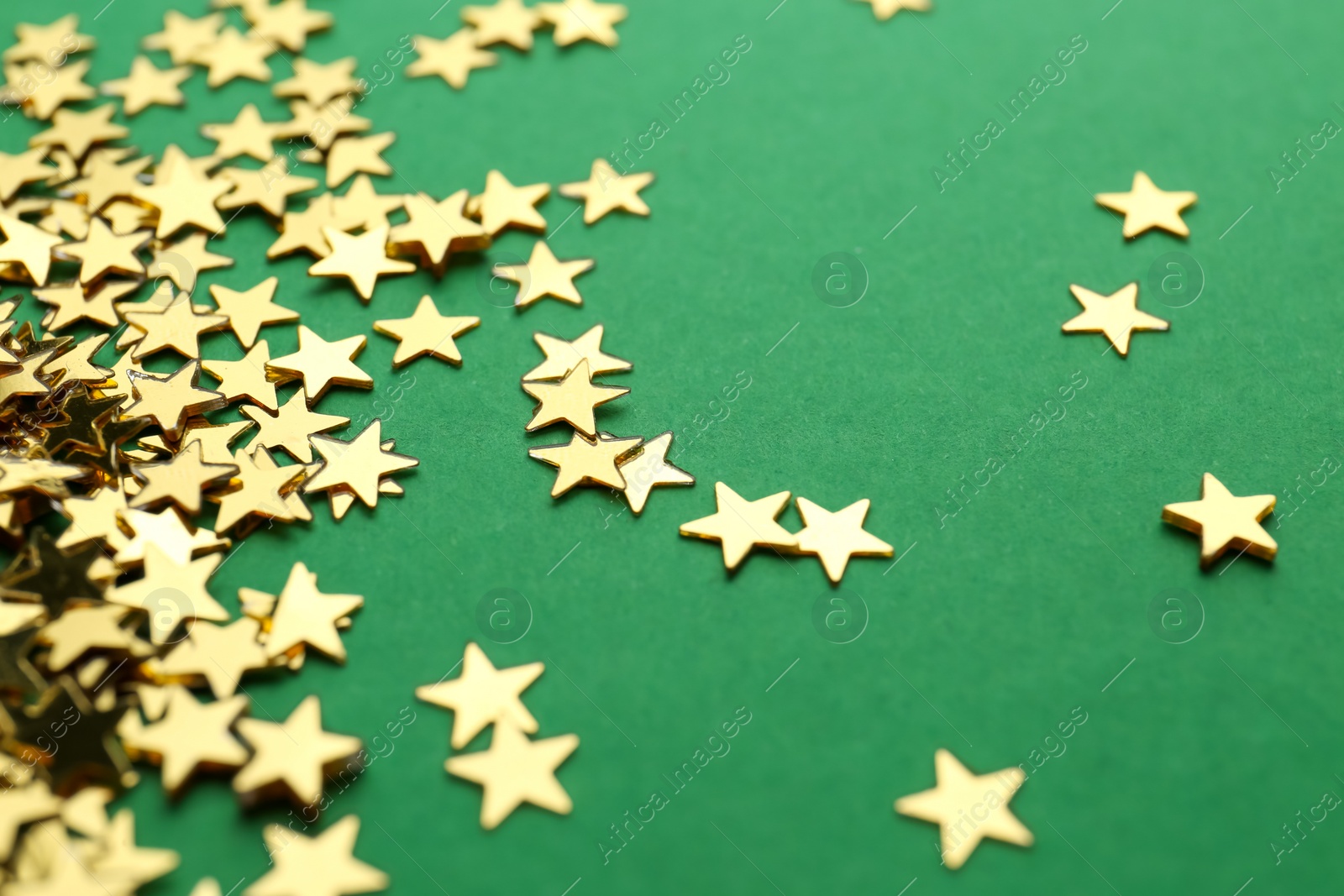 Photo of Confetti stars on green background, closeup. Christmas celebration