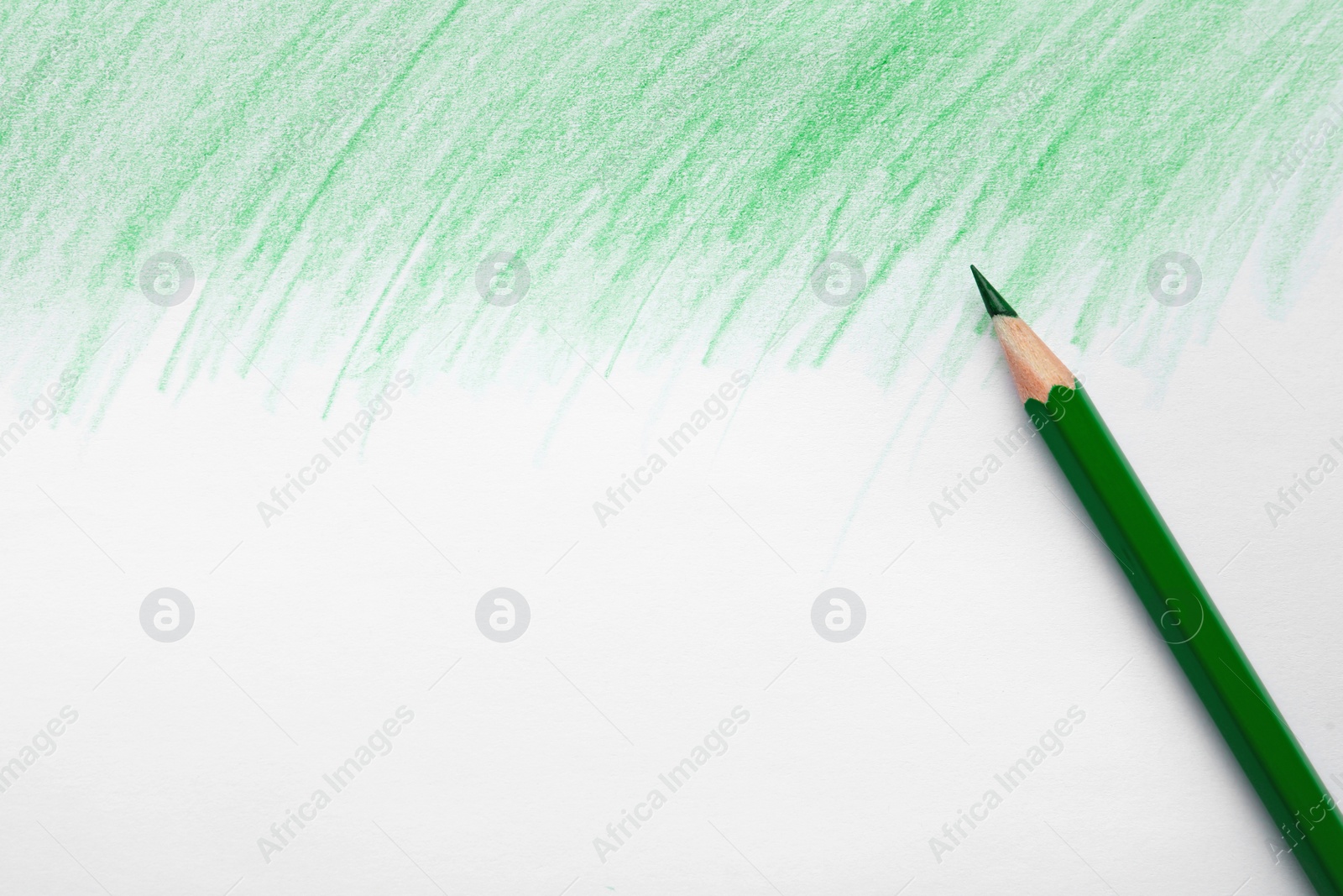 Photo of Green pencil on sheet of paper with drawing, top view. Space for text