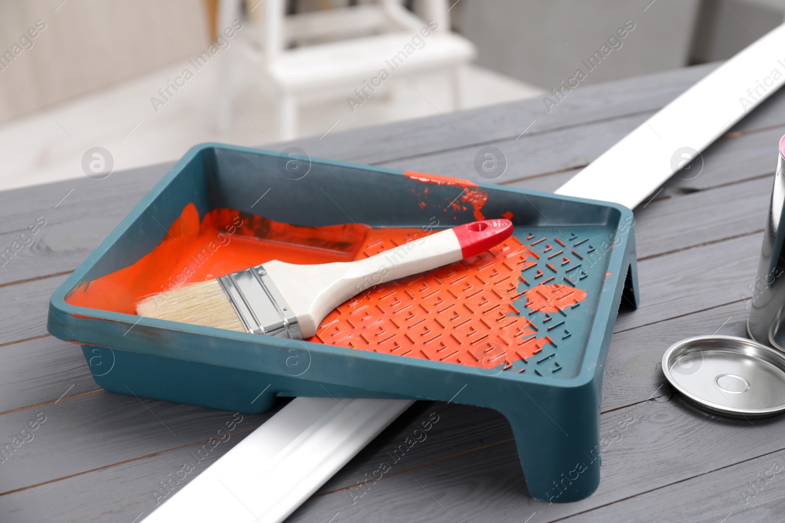Photo of Tray with orange paint and brush on grey wooden table indoors