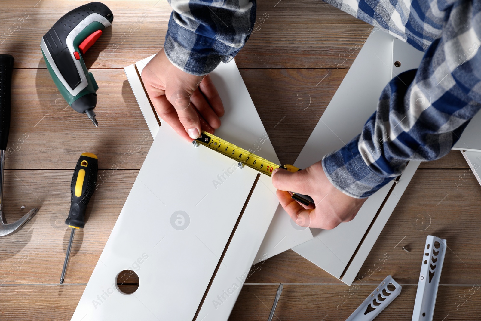 Photo of Man assembling furniture at wooden table, closeup