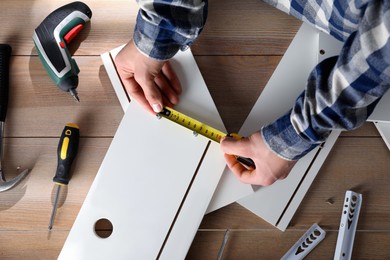 Man assembling furniture at wooden table, closeup