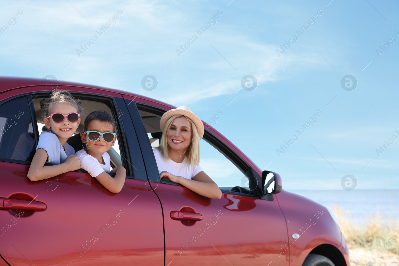 Photo of Happy family in car at beach on sunny day