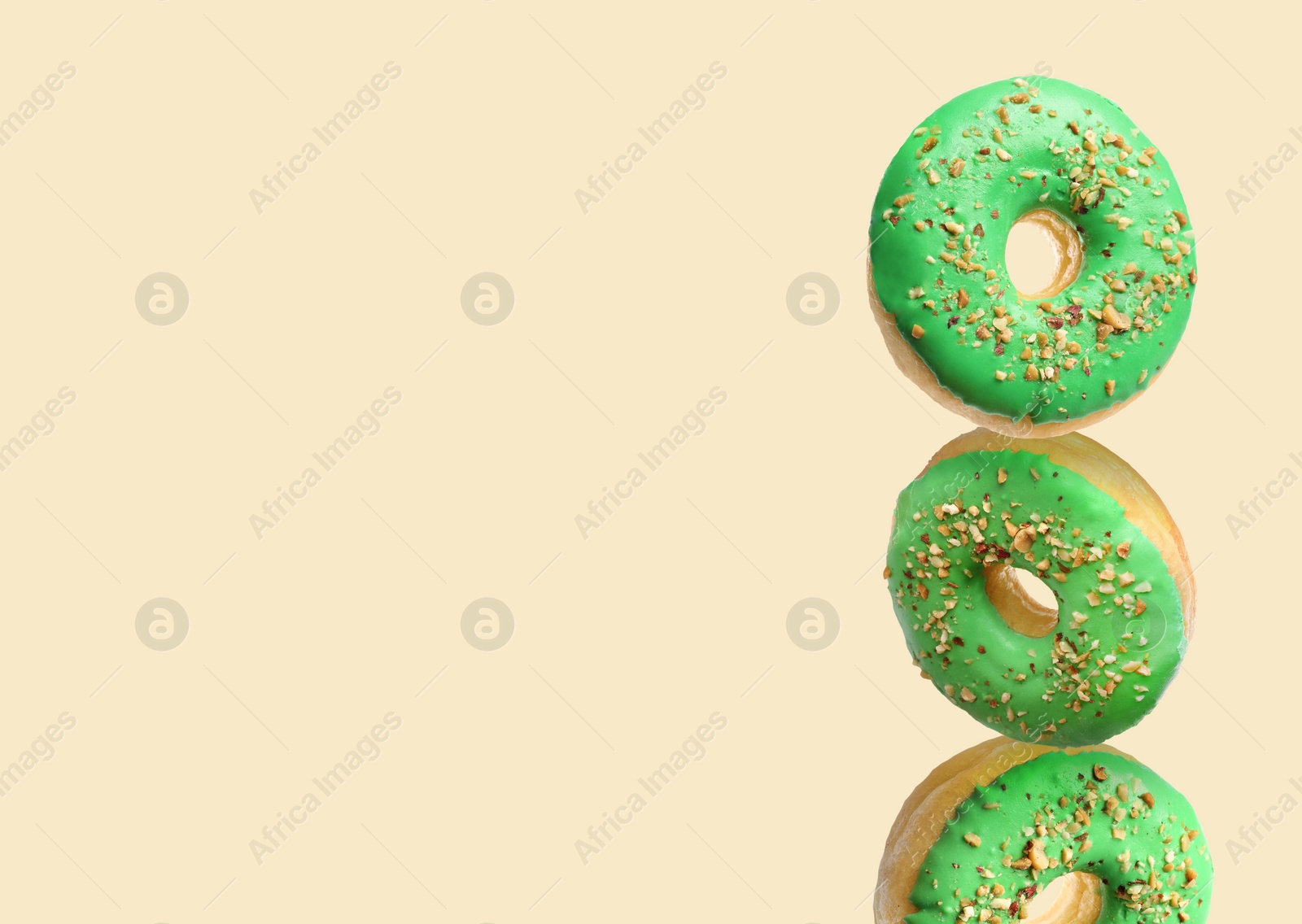 Image of Tasty donuts with sprinkles on beige background, space for text