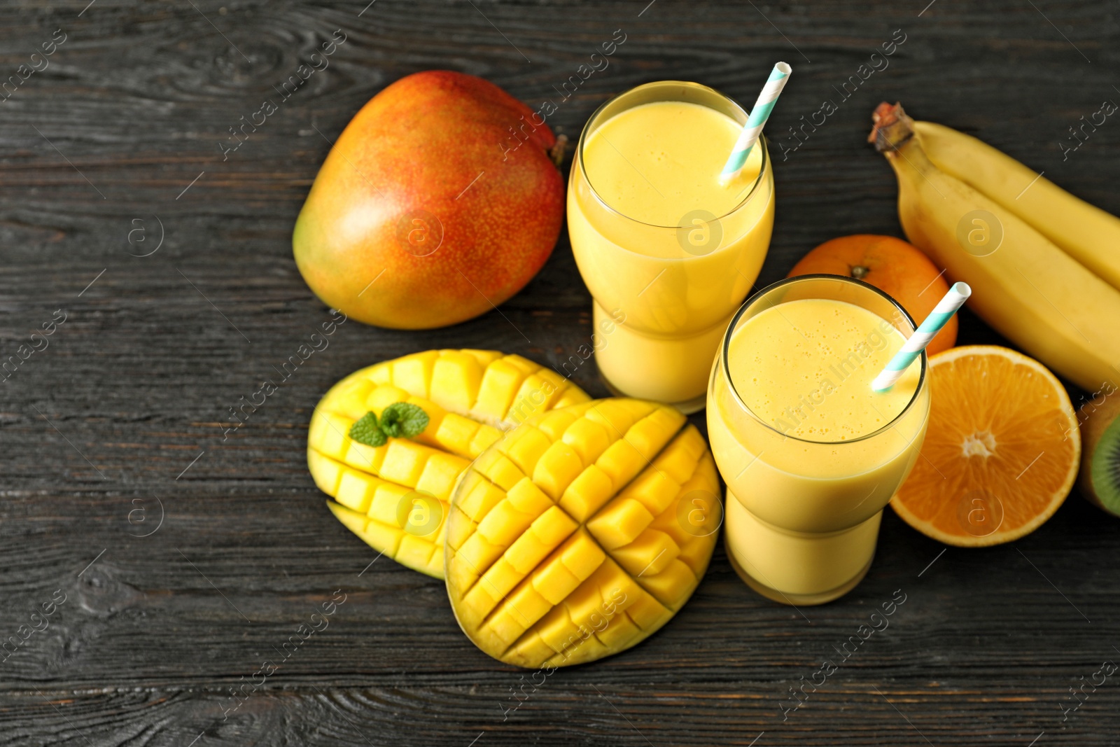 Photo of Tasty tropical drink with mango and fresh fruits on wooden table