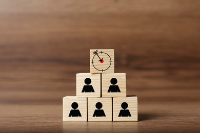 Image of Pyramid of cubes with target and human icons on wooden table