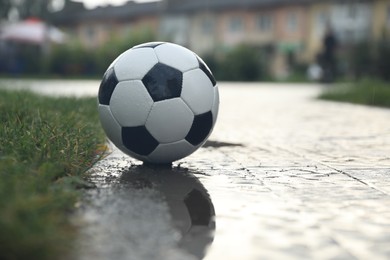 Photo of Wet leather soccer ball on street, space for text