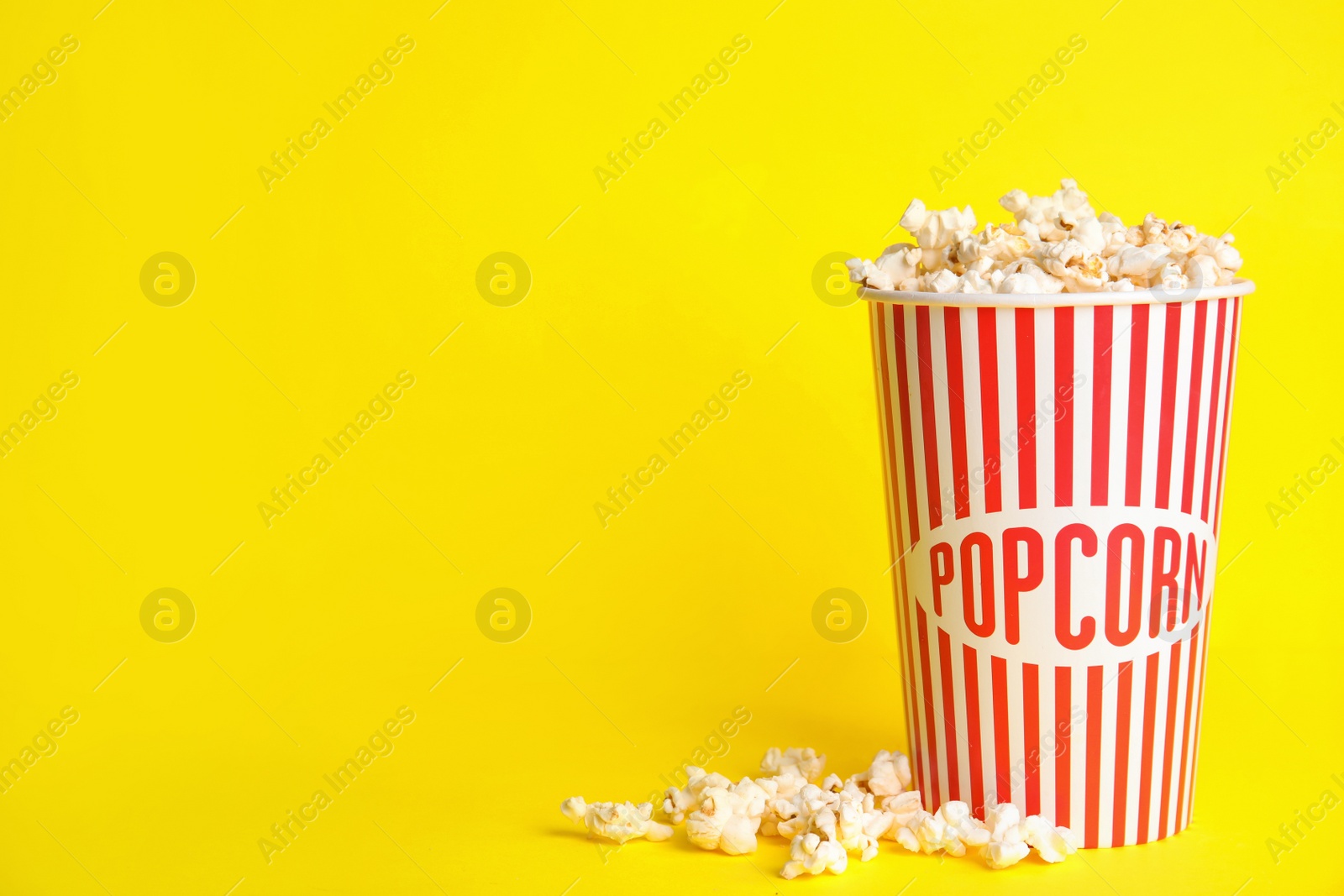 Photo of Tasty pop corn on yellow background, space for text