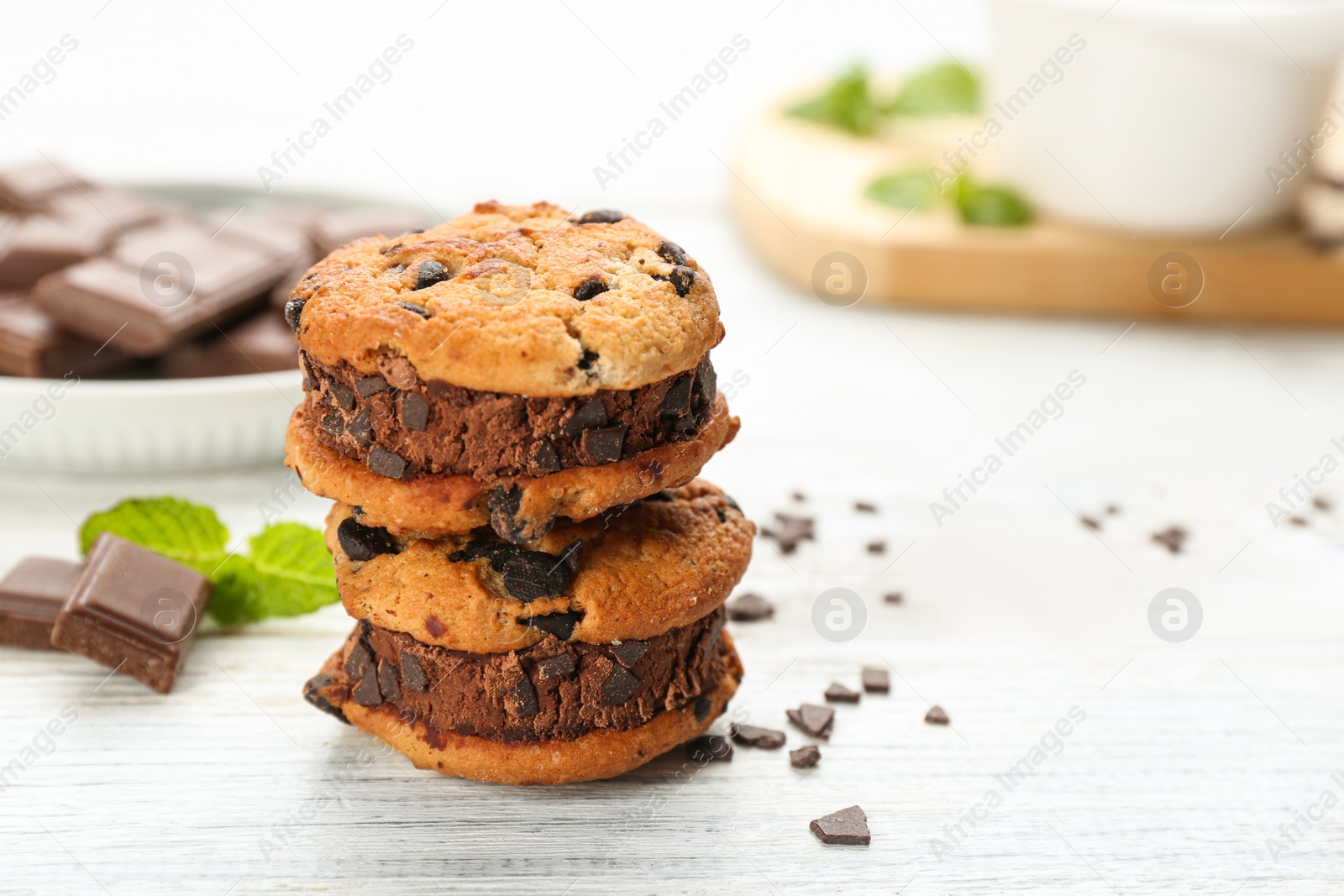 Photo of Sweet delicious ice cream cookie sandwiches on white wooden table. Space for text