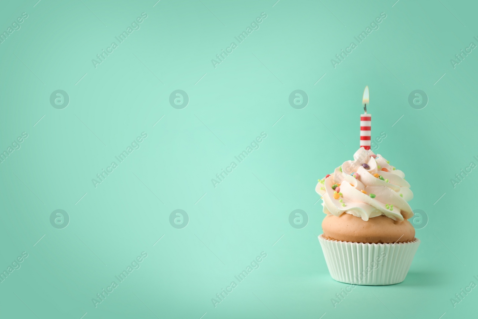 Photo of Delicious birthday cupcake with candle on light green background. Space for text