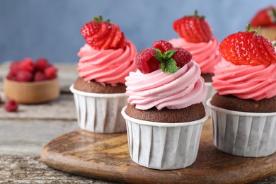 Photo of Sweet cupcakes with fresh berries on wooden table, closeup