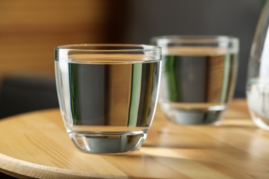 Glass of water on wooden table in room, closeup. Refreshing drink