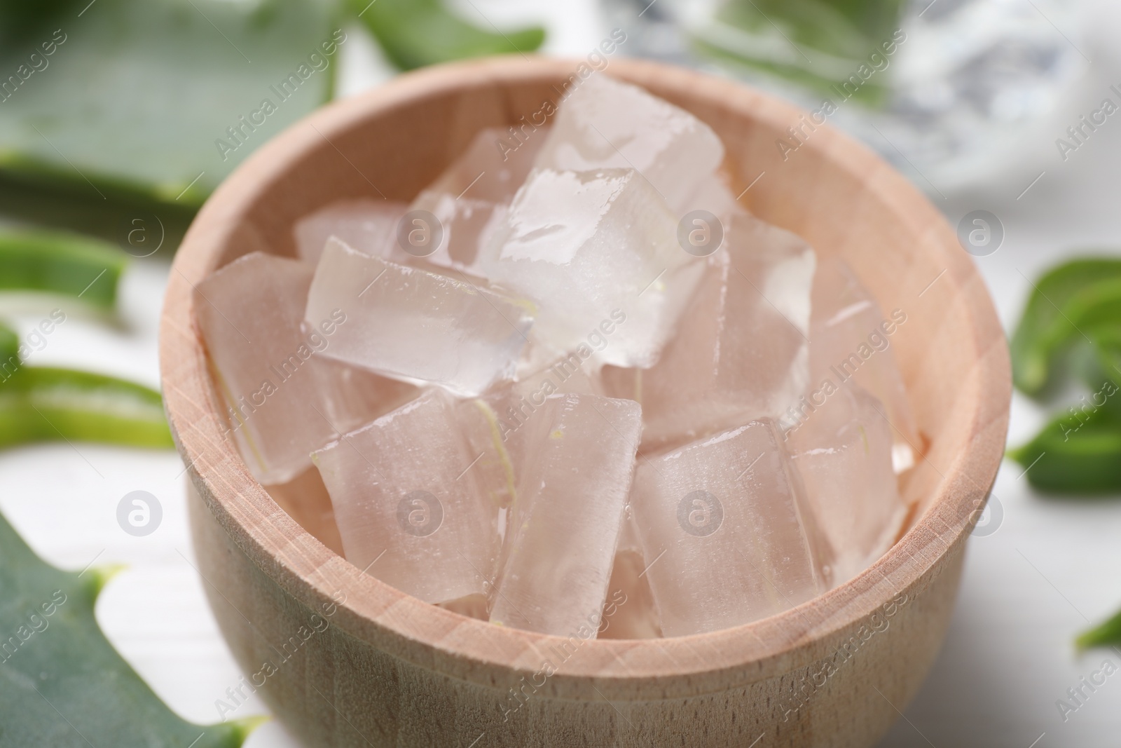 Photo of Aloe vera gel and slices of plant on white table, closeup