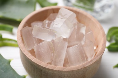 Aloe vera gel and slices of plant on white table, closeup