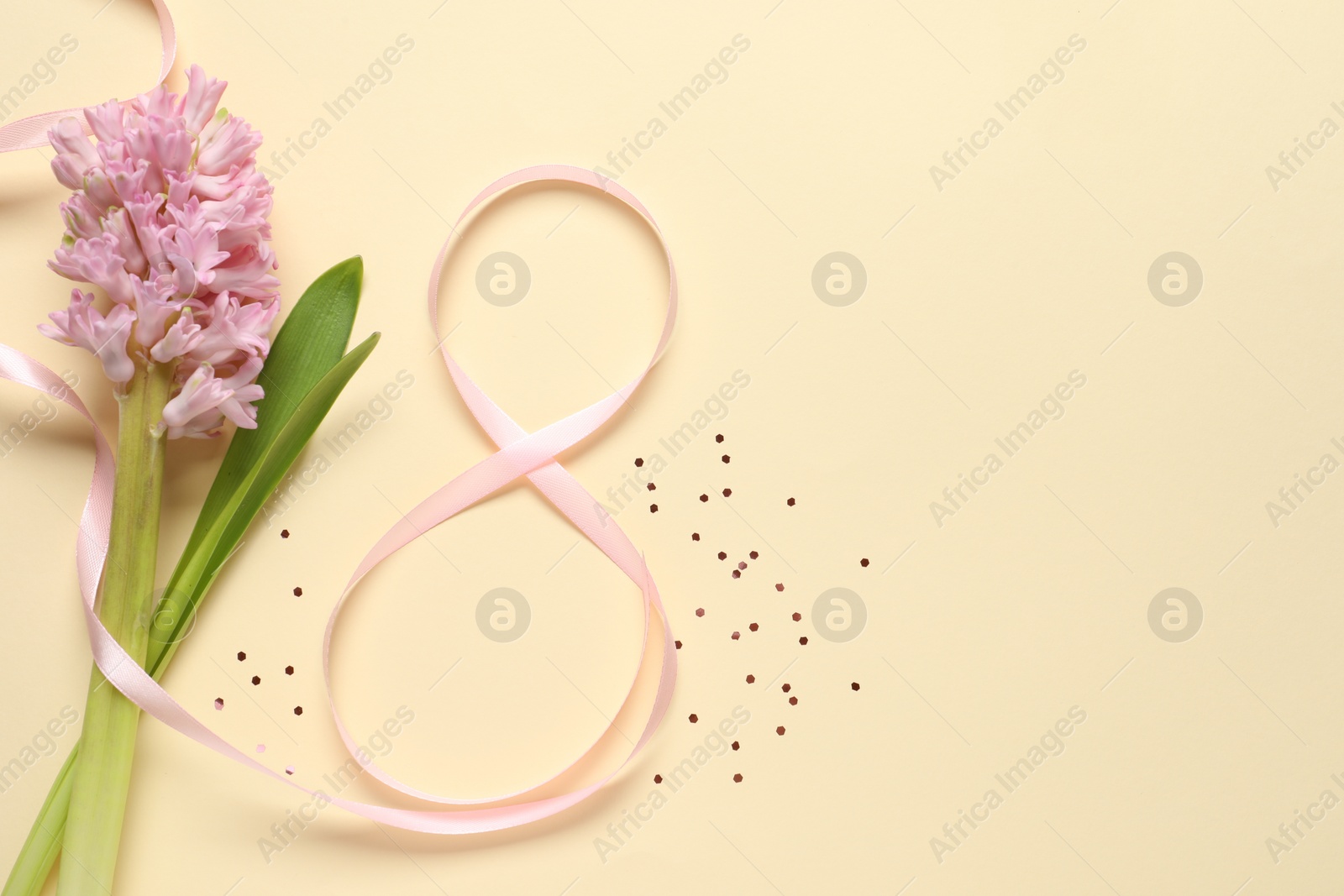 Photo of 8th of March greeting card design with pink ribbon, beautiful flowers and space for text on beige background, flat lay. International Women's day