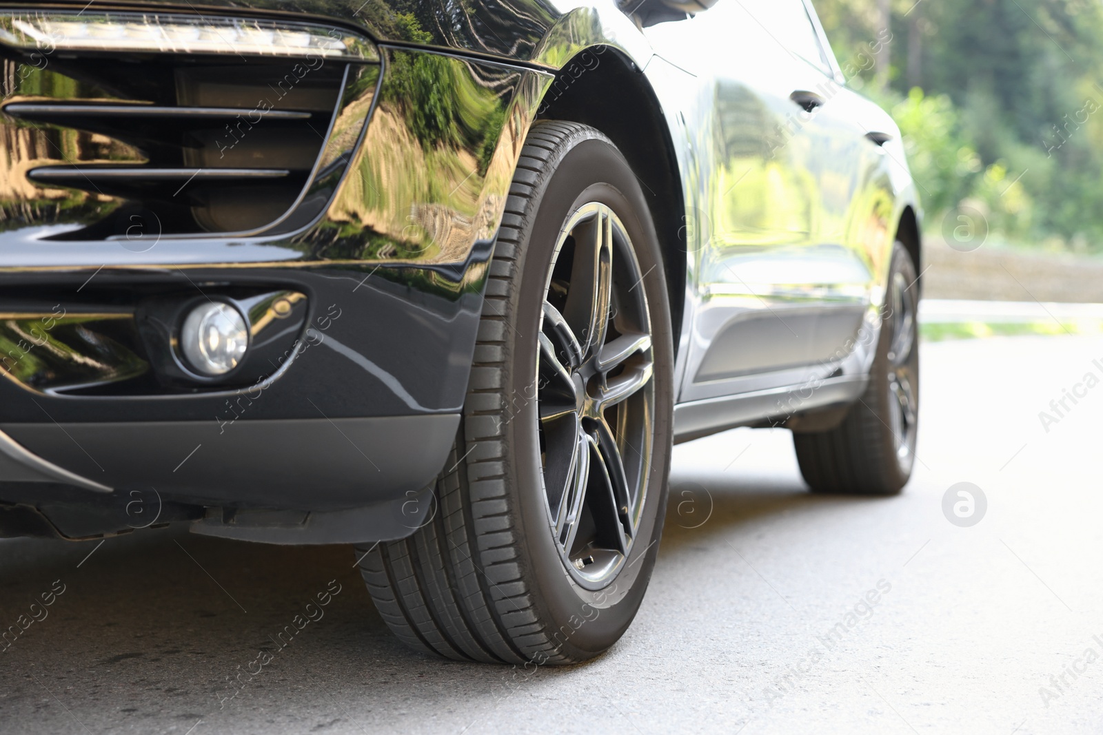 Photo of Modern black car parked on asphalt road outdoors