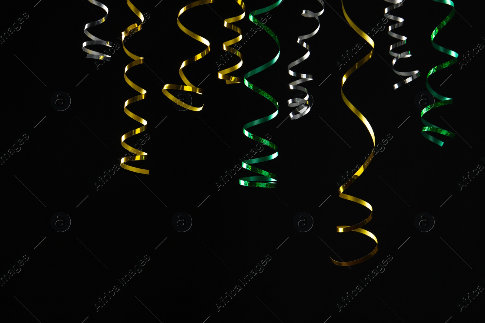 Photo of Many colorful serpentine streamers on black background