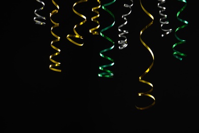 Photo of Many colorful serpentine streamers on black background