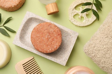 Photo of Flat lay composition of solid shampoo bars, loofah and comb on green background. Hair care