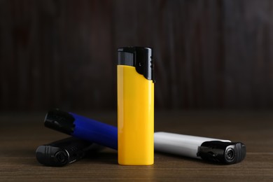 Photo of Stylish small pocket lighters on wooden table