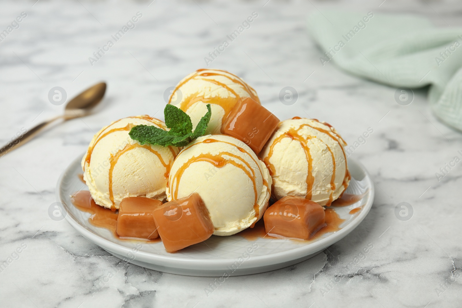 Photo of Delicious ice cream served with caramel and sauce on marble table