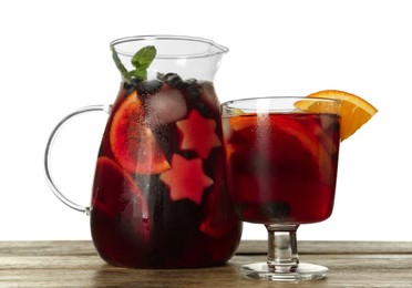 Glass and jug of Red Sangria on wooden table against white background
