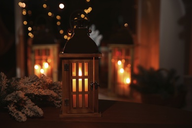 Stylish lantern with burning candle and Christmas decor on table indoors, space for text. Interior design